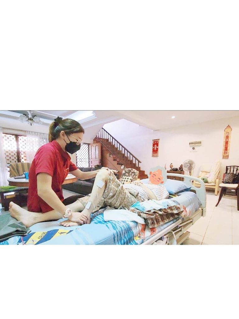 "Ocare Physio therapist providing home visit rehabilitation for a bedridden elderly patient, performing passive leg exercises and electrical stimulation to prevent muscle atrophy."